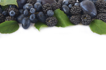 Group of fresh fruits and berries on a white background. Ripe blueberries, blackberries and grapes. Top view with copy space.