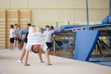 The young man performs gymnastic exercises in the gymnasium.