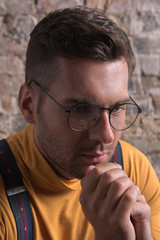 Elegant guy with stubble and glasses thinking with sadness