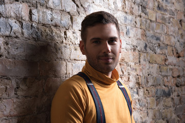 Obraz premium Casual youthful man sitting against brick wall