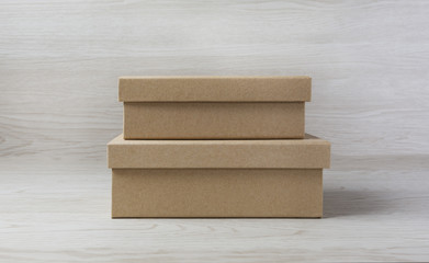 Two small raw plain boxes for small items on white wooden background. With shadow.