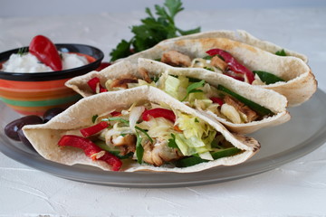 Pita filled with grilled chicken fillet, fresh salad, cucumber, sweet paprika, onion and yogurt sause on a white abstract background. Home cooking. Easy and quick snack