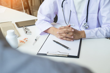 patient listening intently to a male doctor explaining patient symptoms or asking a question as they discuss paperwork together in a consultation