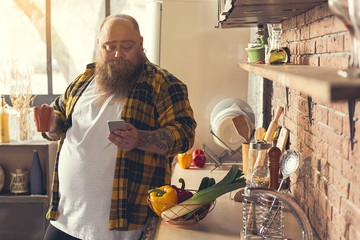 Man holding a cup and looking at his phone