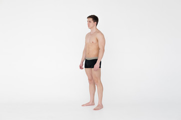 Fototapeta premium studio portrait young sexy men bodybuilder athlete, with a bare torso, Standing in full length on a white background in underwear underwear, Belt is photographed, gold chain with a cross on the neck