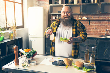 Cheerful thick guy enjoying burger preparation