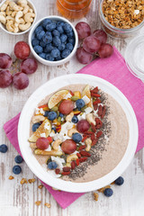 oatmeal with assorted fruits, nuts and chia, top view