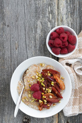 oatmeal with baked fruit for breakfast on wooden table, vertical, top view