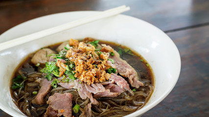 Noodles with pork on a wooden background (Thai noodles).