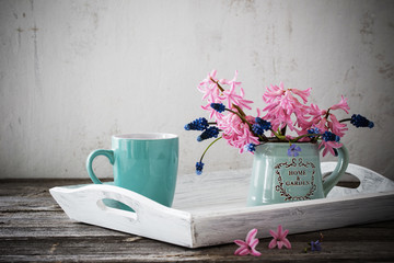 A cup of coffee and a bouquet of flowers on a wooden table