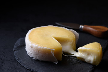 Soft cheese on a slate with cheese knife on background