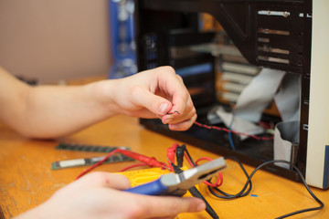 Young man hands cutting a wire of computer and trying to repair (color toned image)