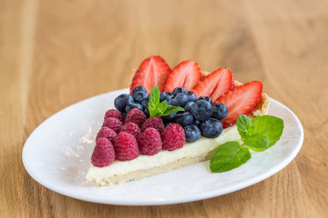 Tart with strawberries and berreis and whipped cream decorated with mint leaves