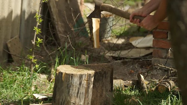 The logger cuts wood with an ax.