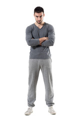 Fototapeta premium Tough young serious athletic sporty man staring at camera with crossed arms. Full body length portrait isolated on white studio background. 