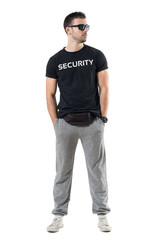 Tough young undercover police agent with waist bag and sunglasses looking away. Full body length portrait isolated on white studio background. 