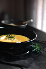 Vegetable soup in black plate and table of dark wood
