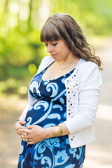 Portrait of young happy pregnant woman relaxing and enjoying life in nature. Outdoor shot.