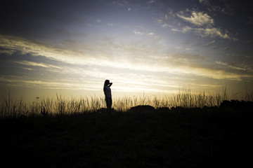Frau steht im Sonnenaufgang in einem Feld