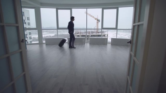 man with suitcase going in empty room. tourist walking through a large hall.