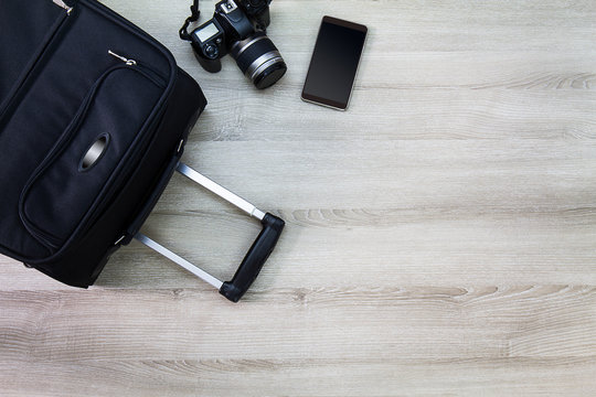 Travelling bag,camera and smartphone on wooden background