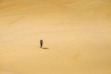 Lonely man moves on hot sand in the desert
