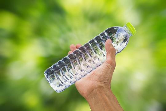 Man's hand holding drinking water bottle on blurred zoom bokeh zoom  background