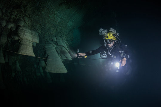 Scuba diver exploring unique natural formations known as "bells" in submerged caves beneath the jungle