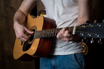 Fototapeta premium Grać na gitarze. Gitara akustyczna w rękach gitarzysty. Rama pozioma