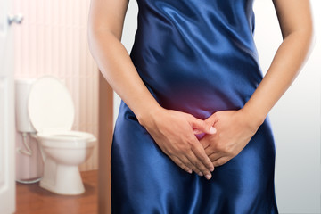 Woman with prostate problem in front of toilet bowl. Lady with hands holding her crotch, People...