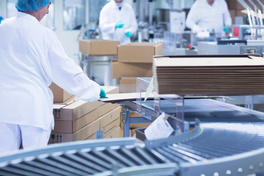 Workers Packaging Pharmaceutical Products On Production Line In Pharmaceutical Plant