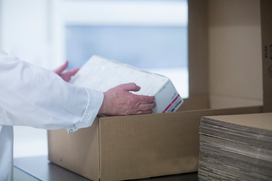 Worker packaging pharmaceutical products in pharmaceutical plant, mid section