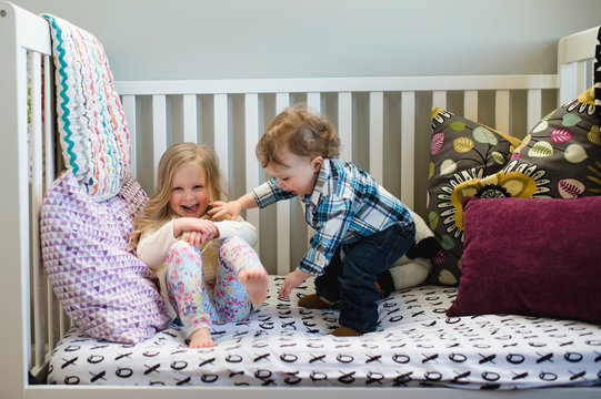 Male toddler and sister playing on day bed
