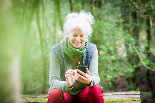 Mature female gardener taking a break looking at smartphone