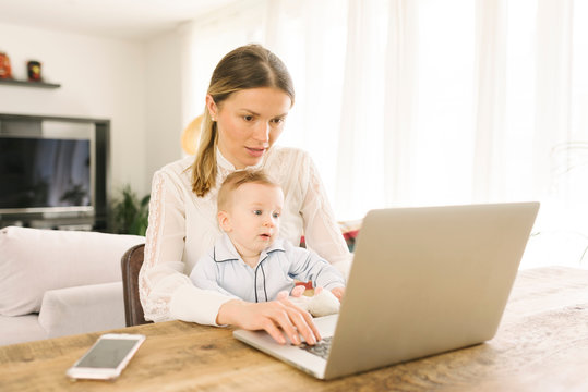 Mother working and caring for baby at home