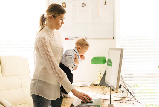 Mother working and caring for baby at home