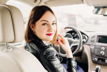 woman in car indoor keeps wheel turning around smiling looking at passengers in back seat idea taxi driver against sunset rays Light shine sky Concept of exam Vehicle - second home the girl