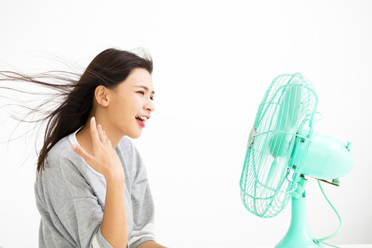 smiling woman cooling herself by electric fan.