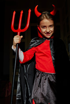 Portrait of girl dressed up as a devil holding a devil's fork