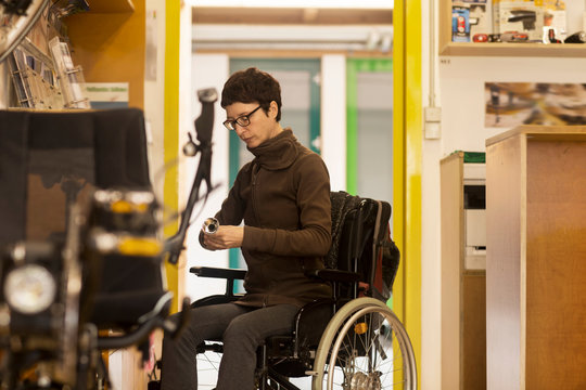 Woman in wheelchair in bicycle repair shop