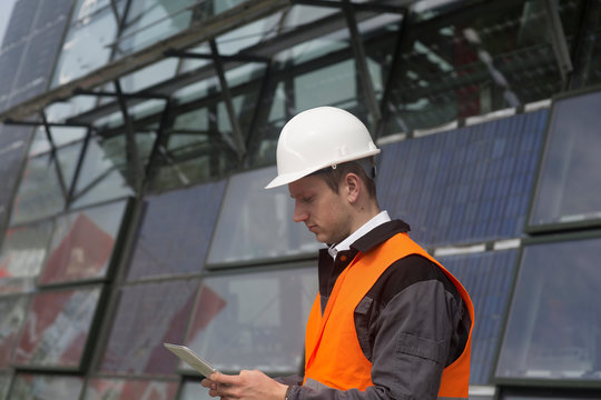 Young male engineer looking at digital tablet at solar panel site