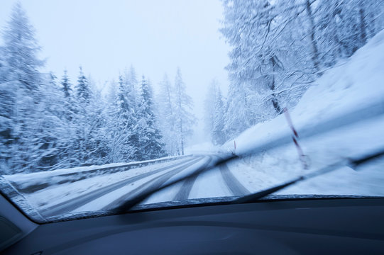 Windscreen view of snow covered rural forest road, Gstaad, Switzerland