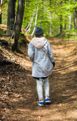 Young woman walking alone in early spring forest