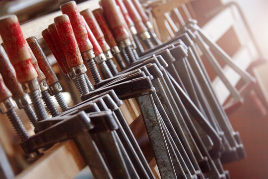 Row of carpenters clamps on workshop shelf