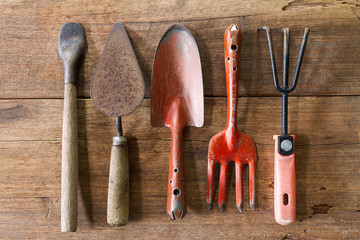 Old dirty grunge rusty gardening tools on dirty grunge wooden background in vintage style