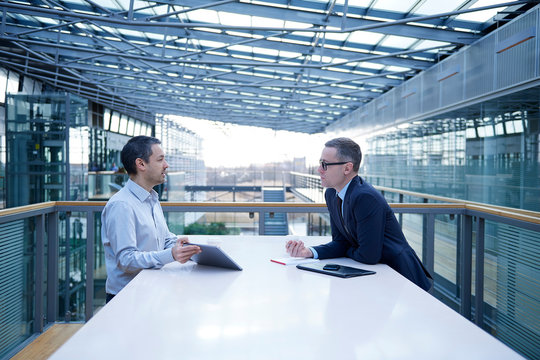 Two businessmen meeting at office balcony table