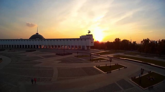 Poklonnaya Hill Victory Park Triumphal. Museum of World War. Bronze sculpture of Horsmen with trumpet.  Moscow Russia. People tourists walk. Summer orange sunset. Aerial Flight around 