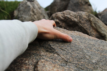 Rock climber's hand grasping handhold on cliff. Depth of field