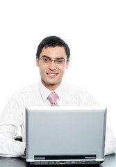 Young happy smiling businessman in glasses working with laptop, isolated