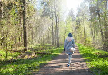 Young woman walking alone in early spring forest